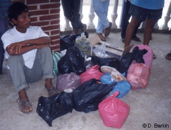 Man resting with collected bags of local seeds for reforestation