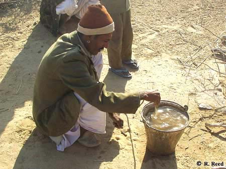 Rajasthani man stirring find sand into surface water to help clear it of particulates