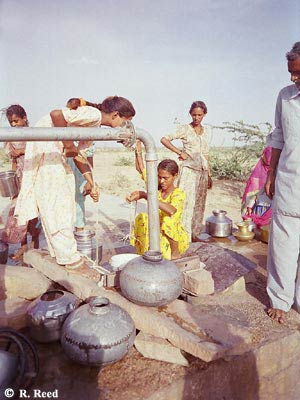 Photo of women and children gathered around the standpipe that is a primary village water source in Tulesar Purohitan, Rajasthan.