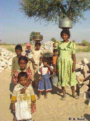 Photo of children carrying water in traditional steel and brass pitchers