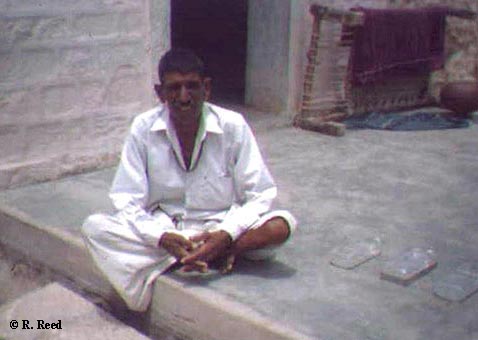 picture of seated man with three solar disinfection bottles laid out on terrace to his right
